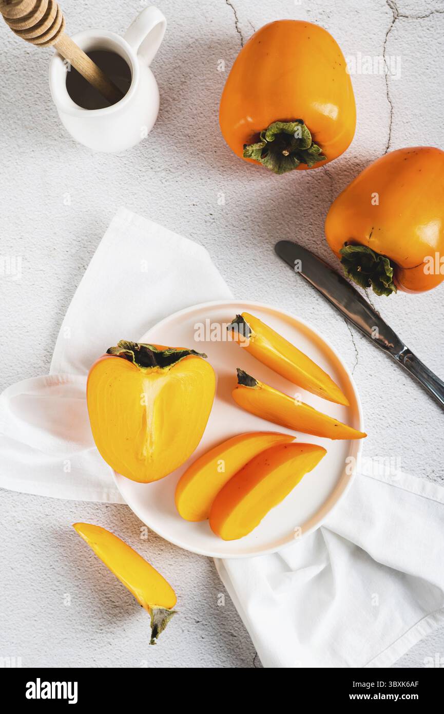 Food, Plate with pieces of sweet tasty persimmon on white background top and vertical view Stock Photo
