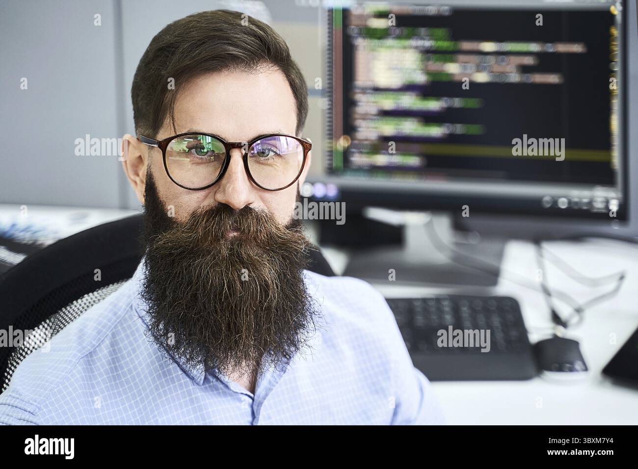 Closeup portrait of a serious computer programmer developer working in IT office, sitting at desk and coding a project in software development company Stock Photo
