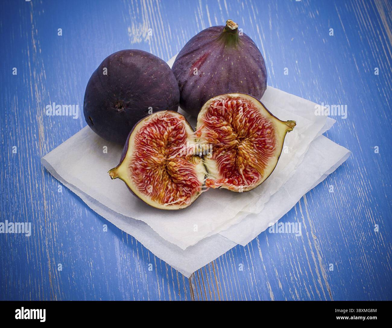 Three ripe figs on baking paper background, top view Stock Photo