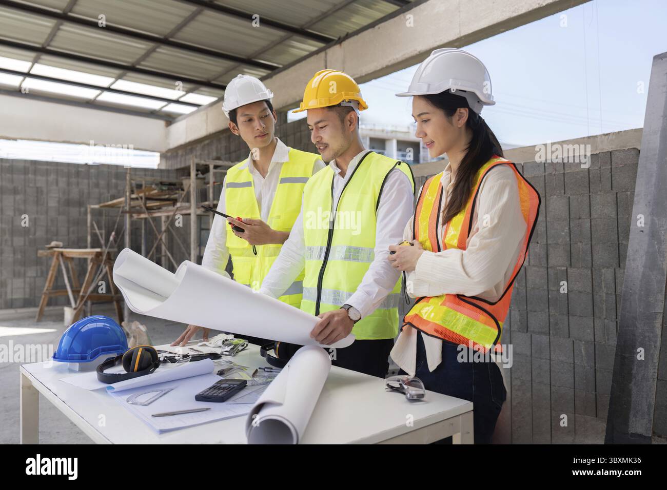Engineers discussing construction blueprints on site, focusing on project execution and design implementation Stock Photo