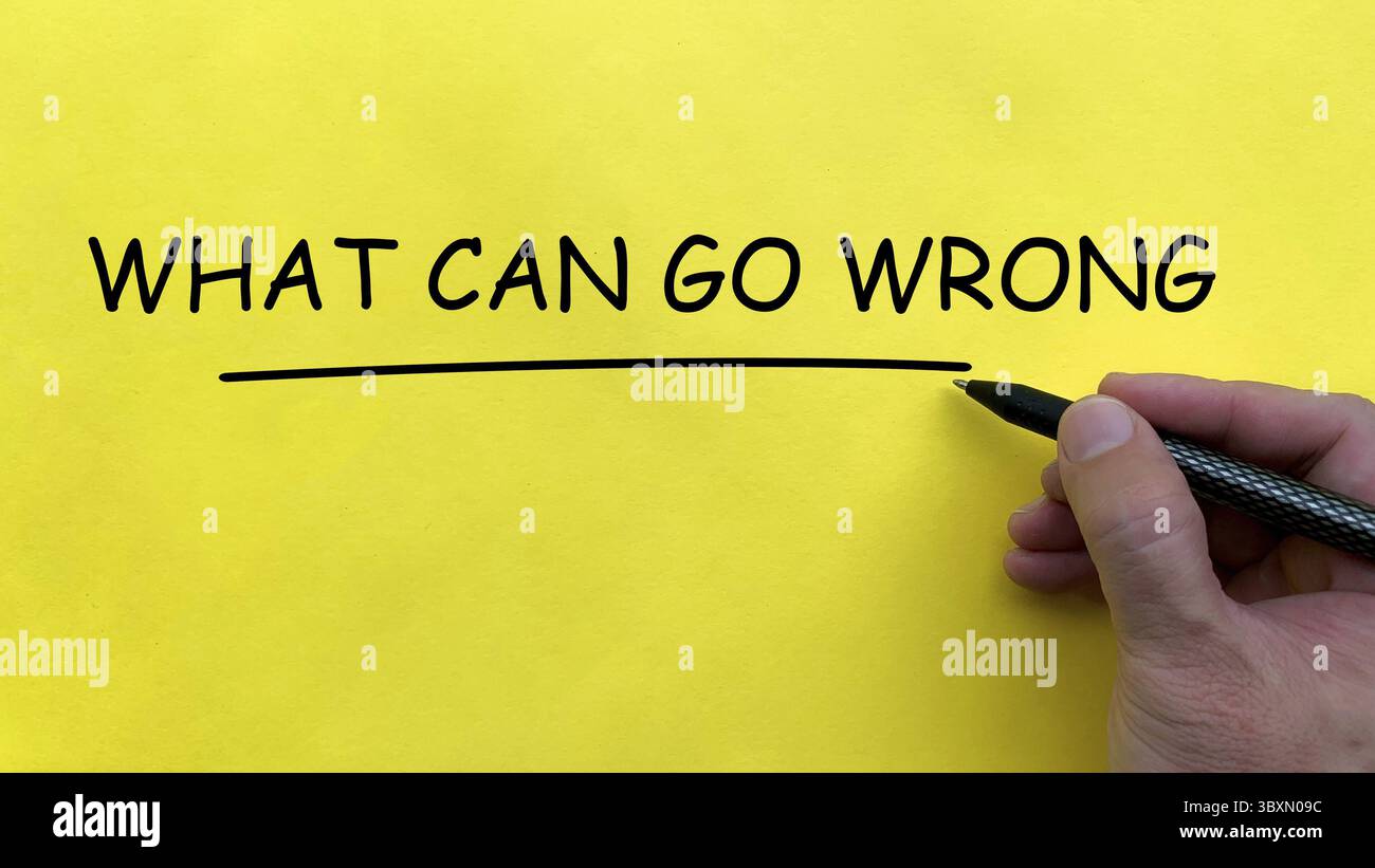 Hand writing What Can Go Wrong text on yellow cover board Stock Photo