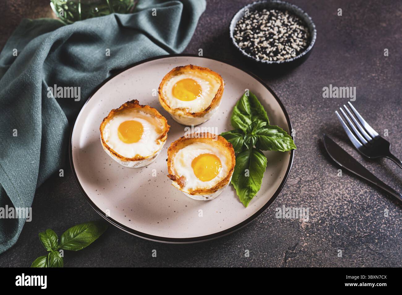 Food, Baked egg and bacon rolls with basil on a plate on a table Stock Photo