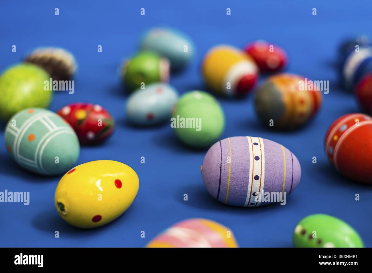 Multicolored wooden eggs on blue background Stock Photo
