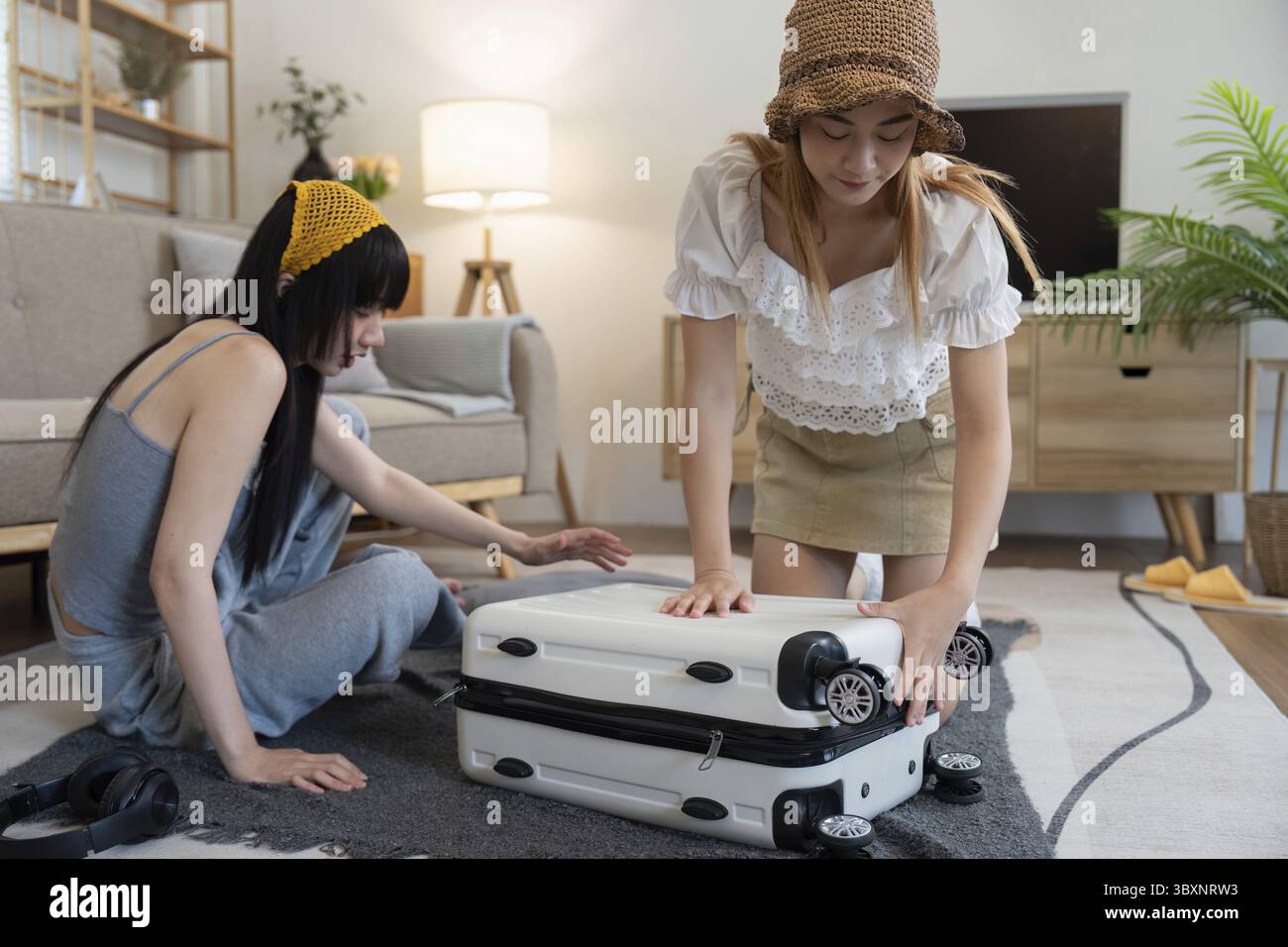 Friendship. Travel together. Two asian young woman friends packing for summer vocation. preparation planning concept Stock Photo