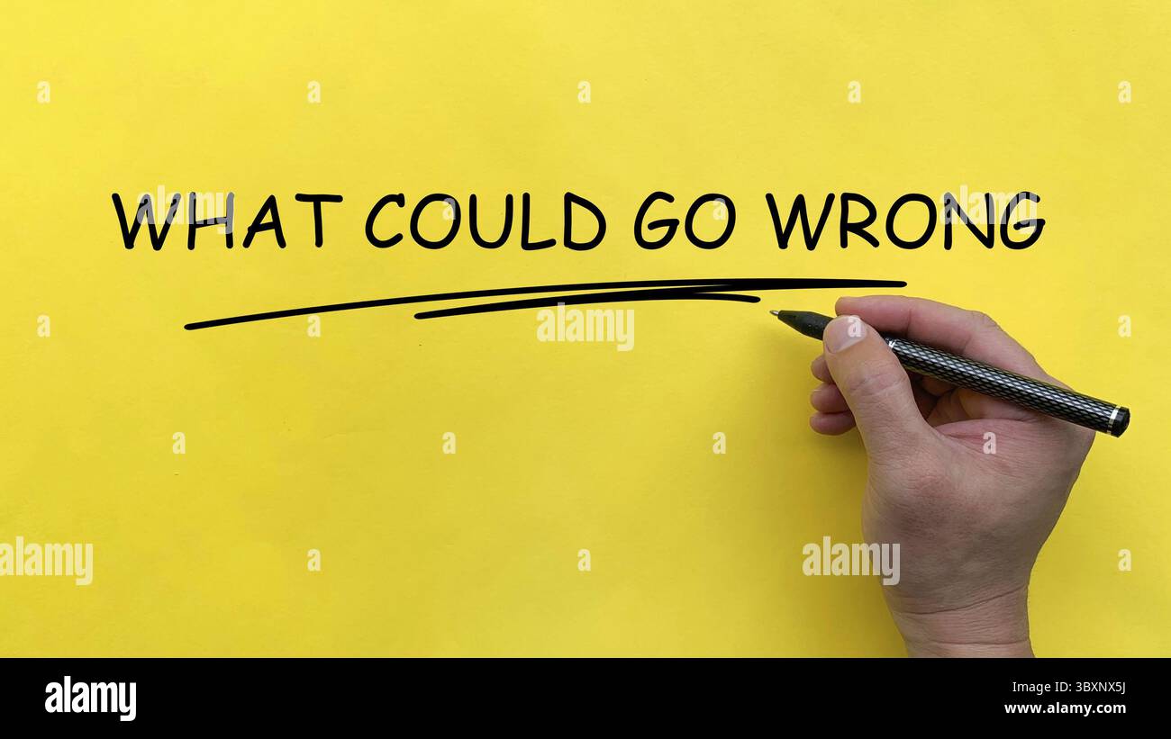 Hand writing What Could Go Wrong text on yellow cover board Stock Photo