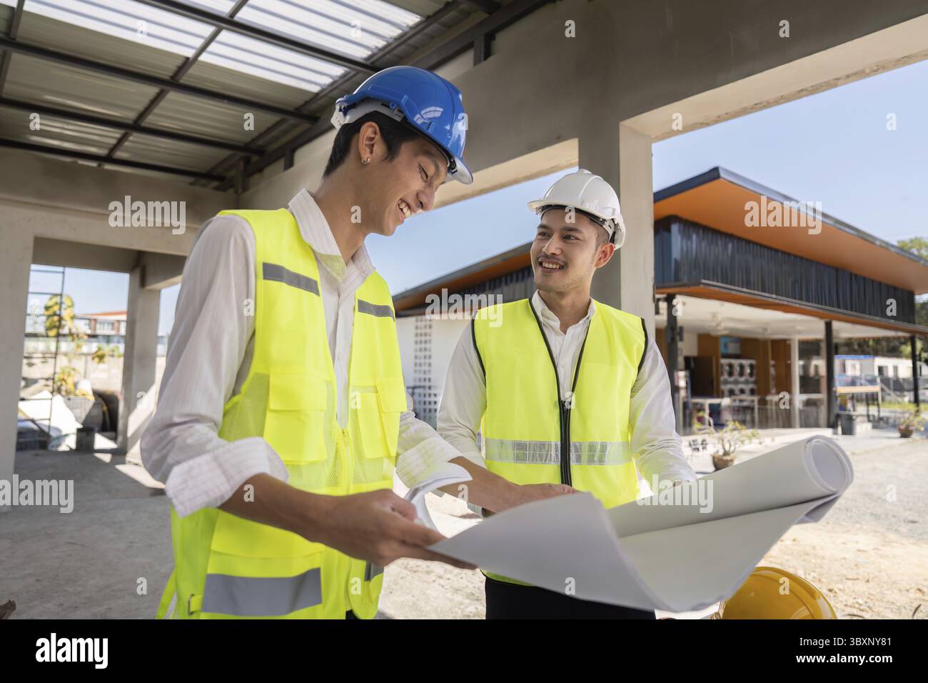 Two construction workers reviewing plans on site, emphasizing communication and strategic planning Stock Photo