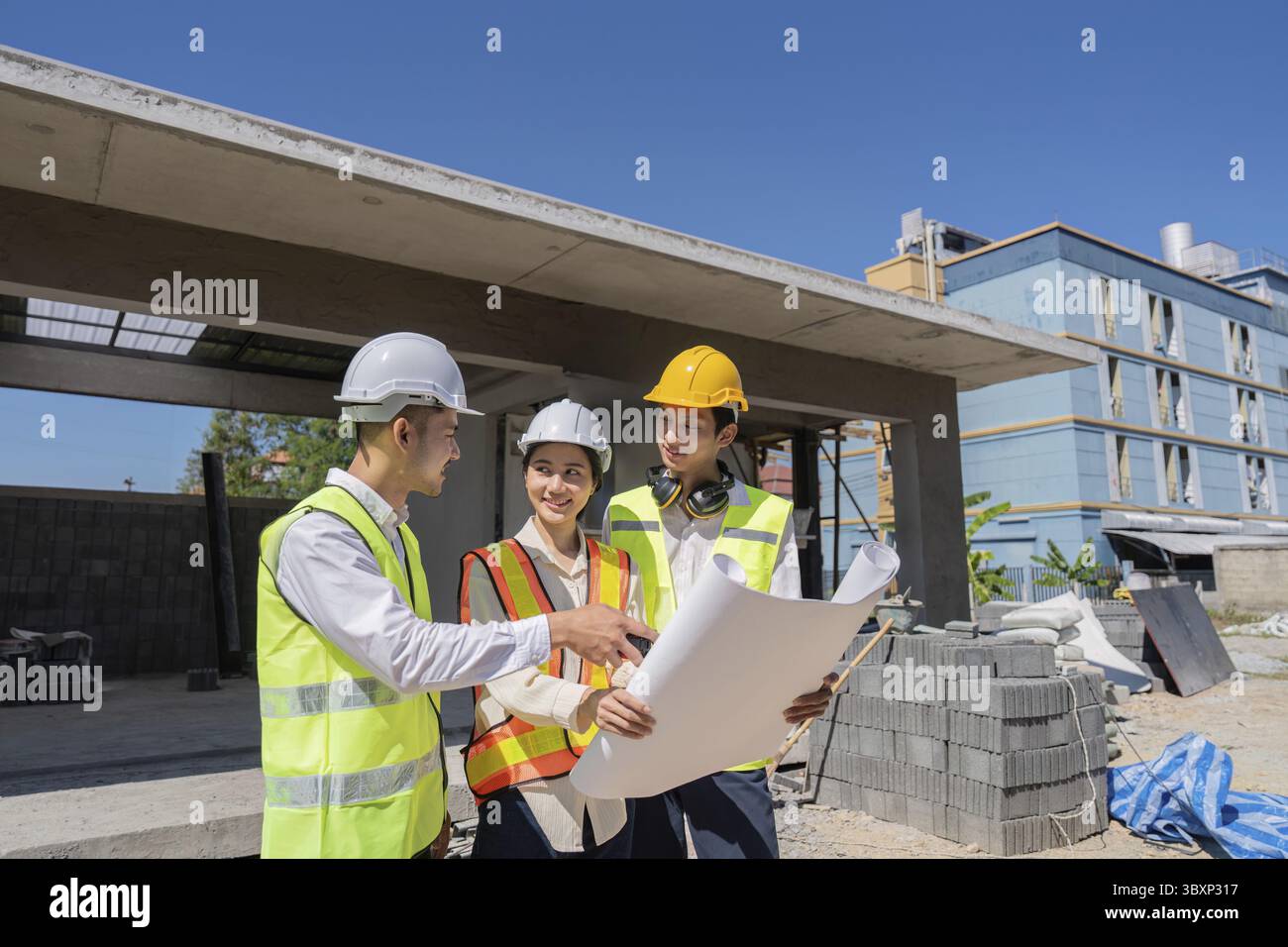 Engineers collaborating on construction plans outdoors, emphasizing teamwork and development for the project Stock Photo