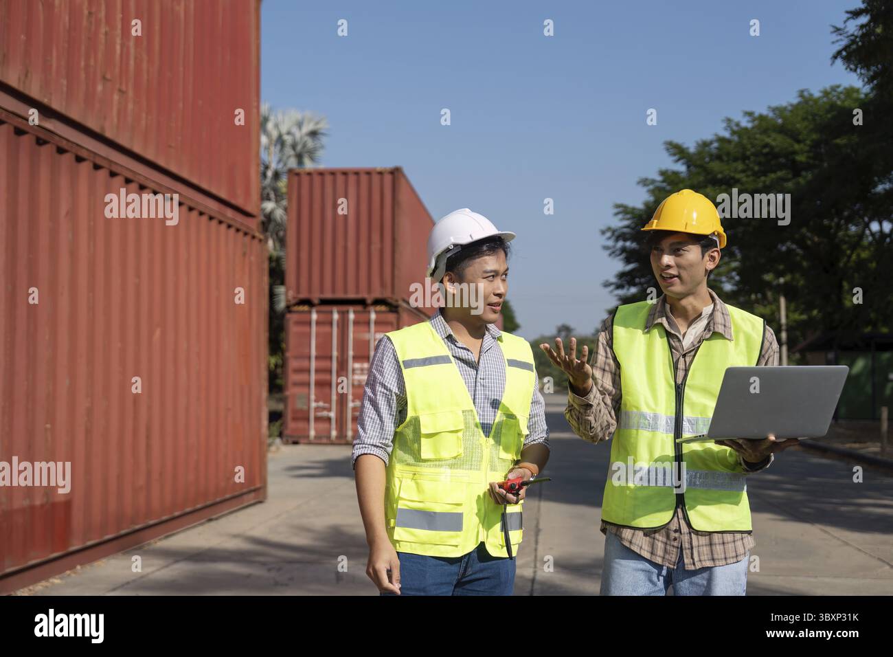 Two engineers engage in a strategic discussion about logistics while using a laptop, emphasizing modern planning techniques Stock Photo