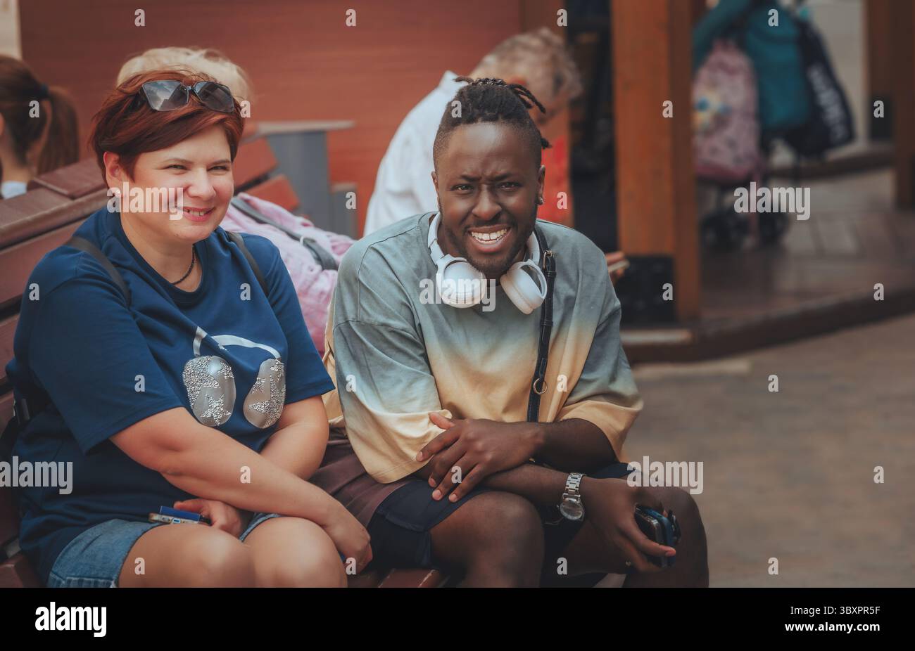 black man and woman sitting on a bench in a park Stock Photo