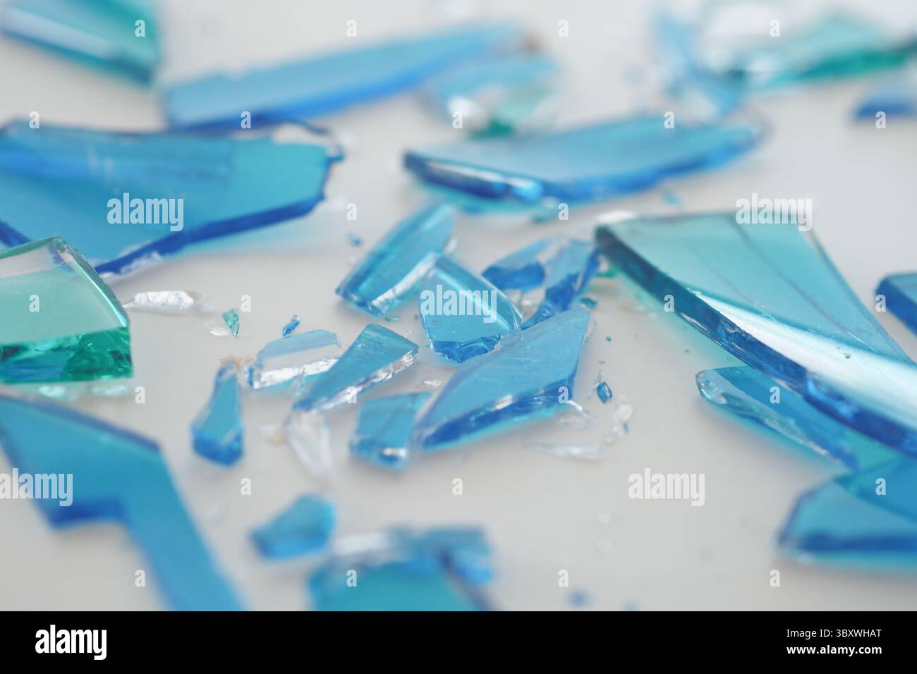 Blue glass shards scattered on a white surface Stock Photo