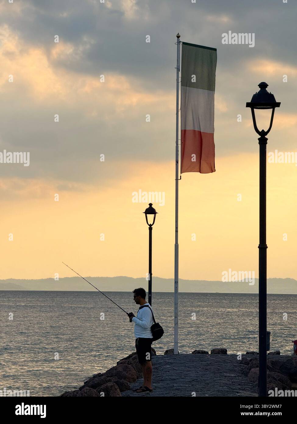 Man fishing on jetty in evening at Cisano on Lake Garda Italy - Smartphone Captured Stock Image
