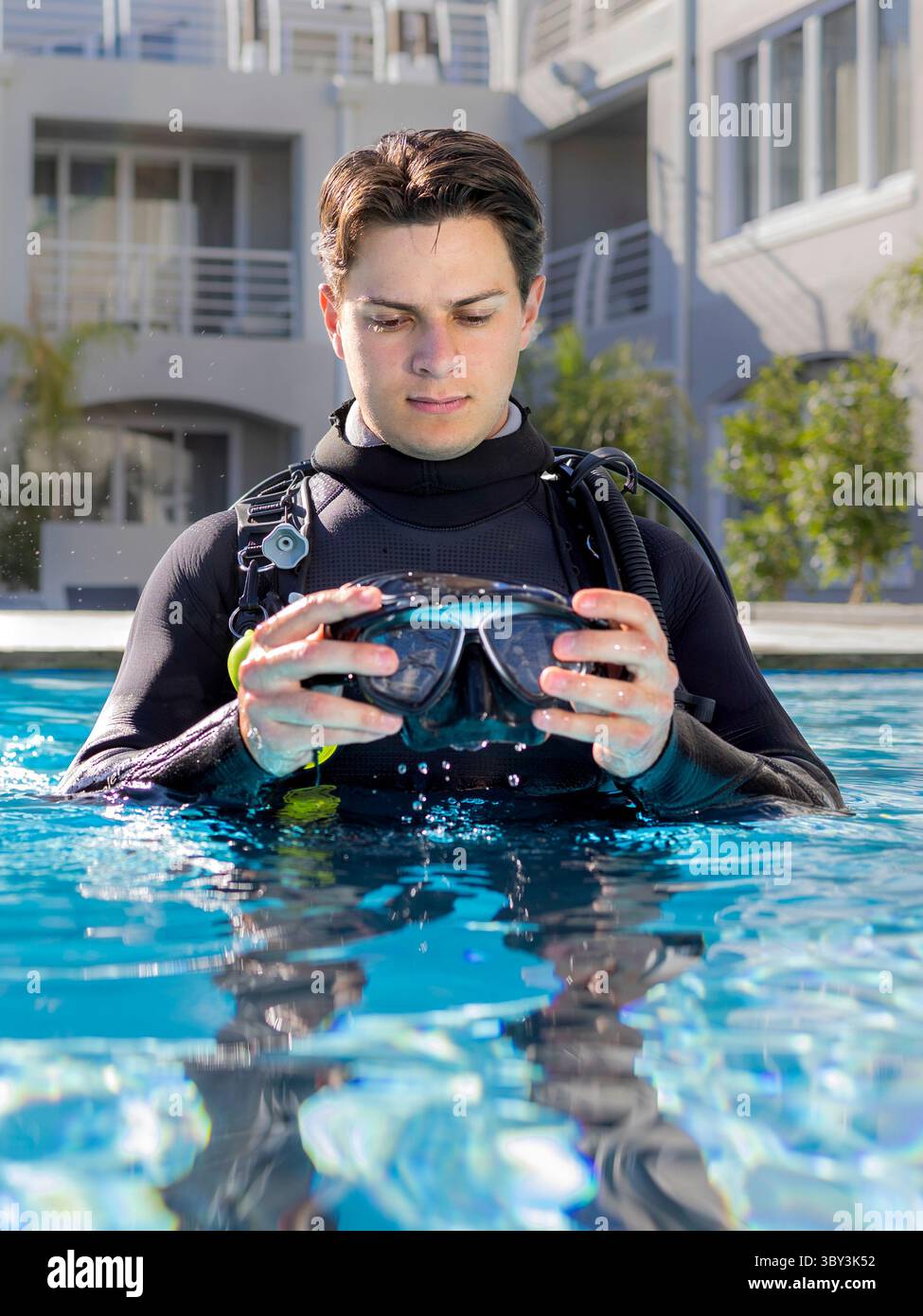 A scuba diver in a pool at a dive resort, wearing a full wetsuit and ...