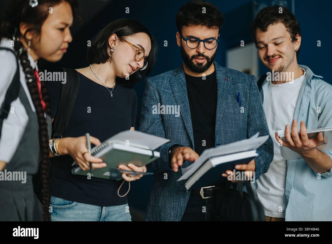 College students engaging in discussion with professor between classes Stock Photo
