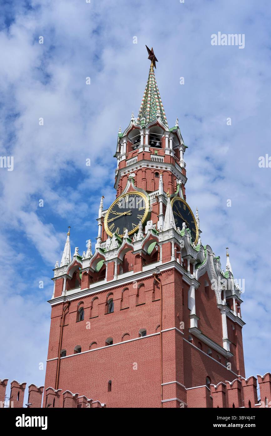 Moscow Kremlin’s Spasskaya Tower with Historic Clock Faces and Red Star Finial against a Cloud-Scattered Sky Stock Photo