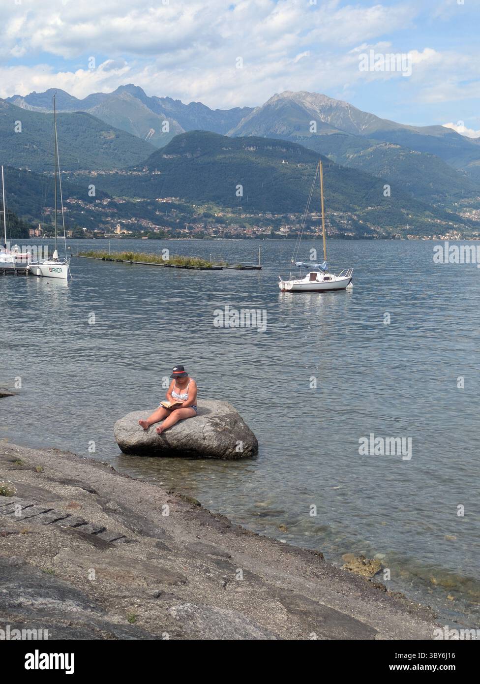 Woman sitting on a stone reading a book Stock Photo