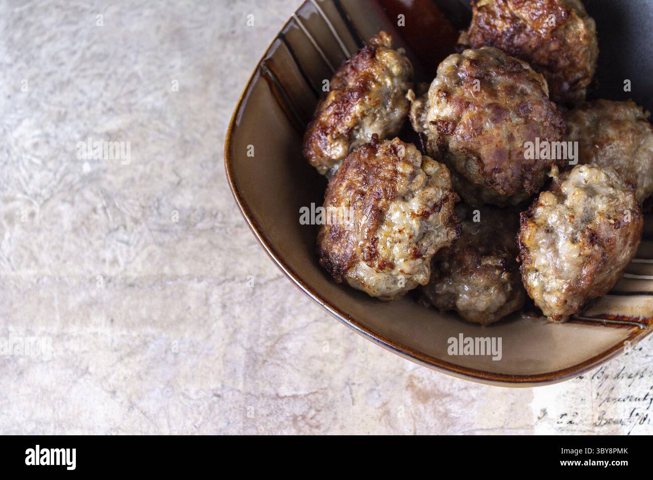 Meatballs lie in a clay plate on a vintage beige background, space for text Stock Photo
