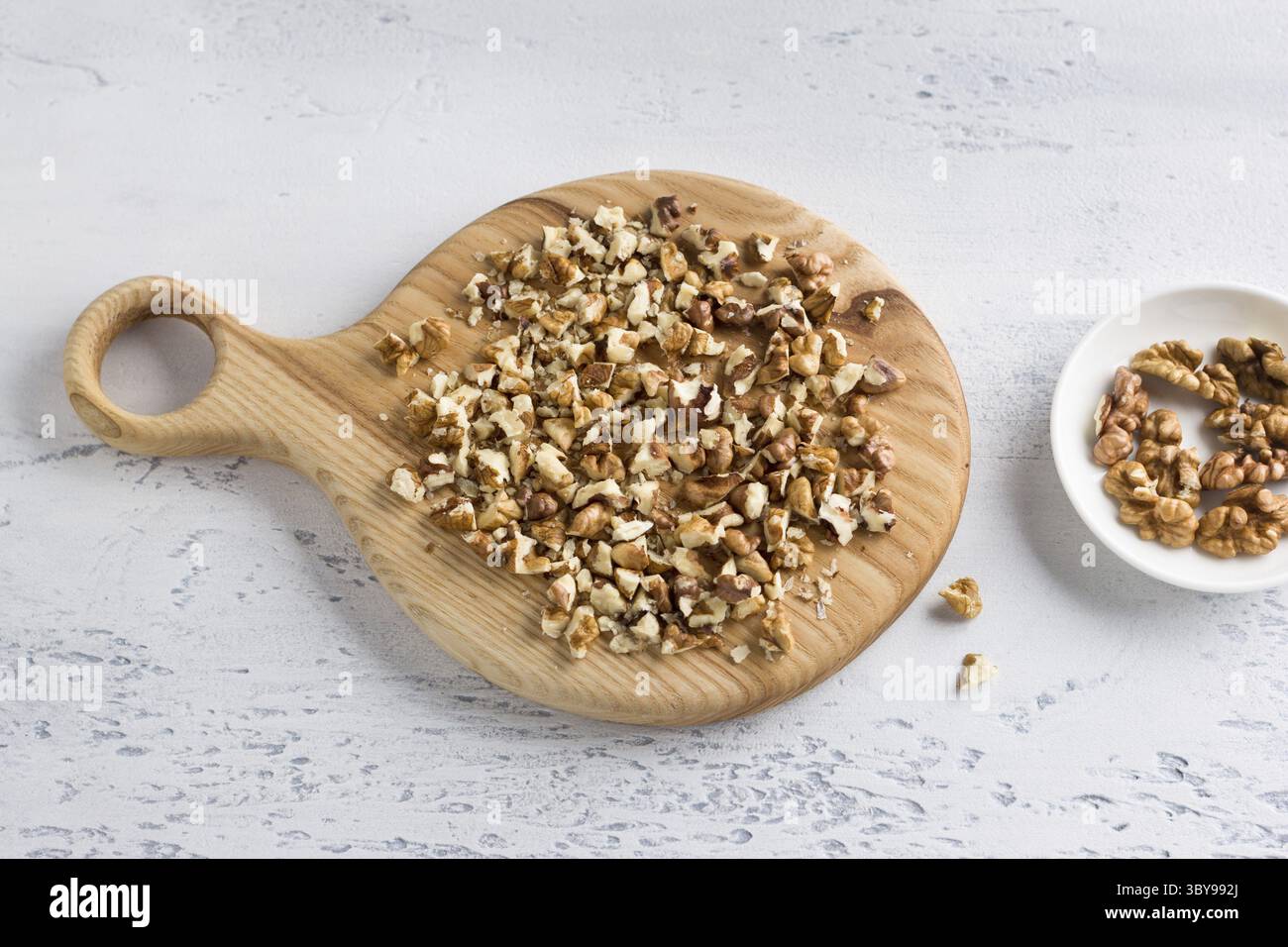 Food, Wooden board with chopped walnut on light blue background, top view Stock Photo