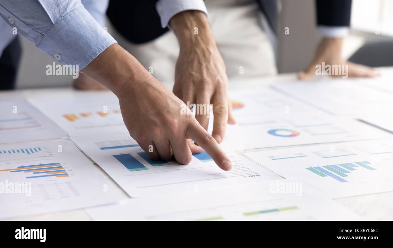 Closeup on hands pointing at charts spread across table Stock Photo - Alamy