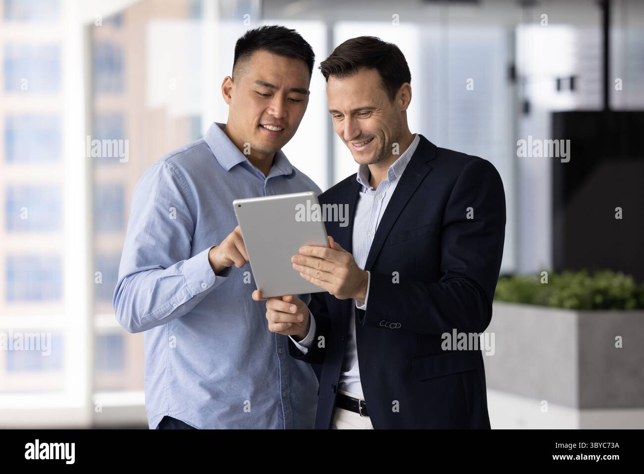 Men teammates reviewing documents or reports using tablet Stock Photo