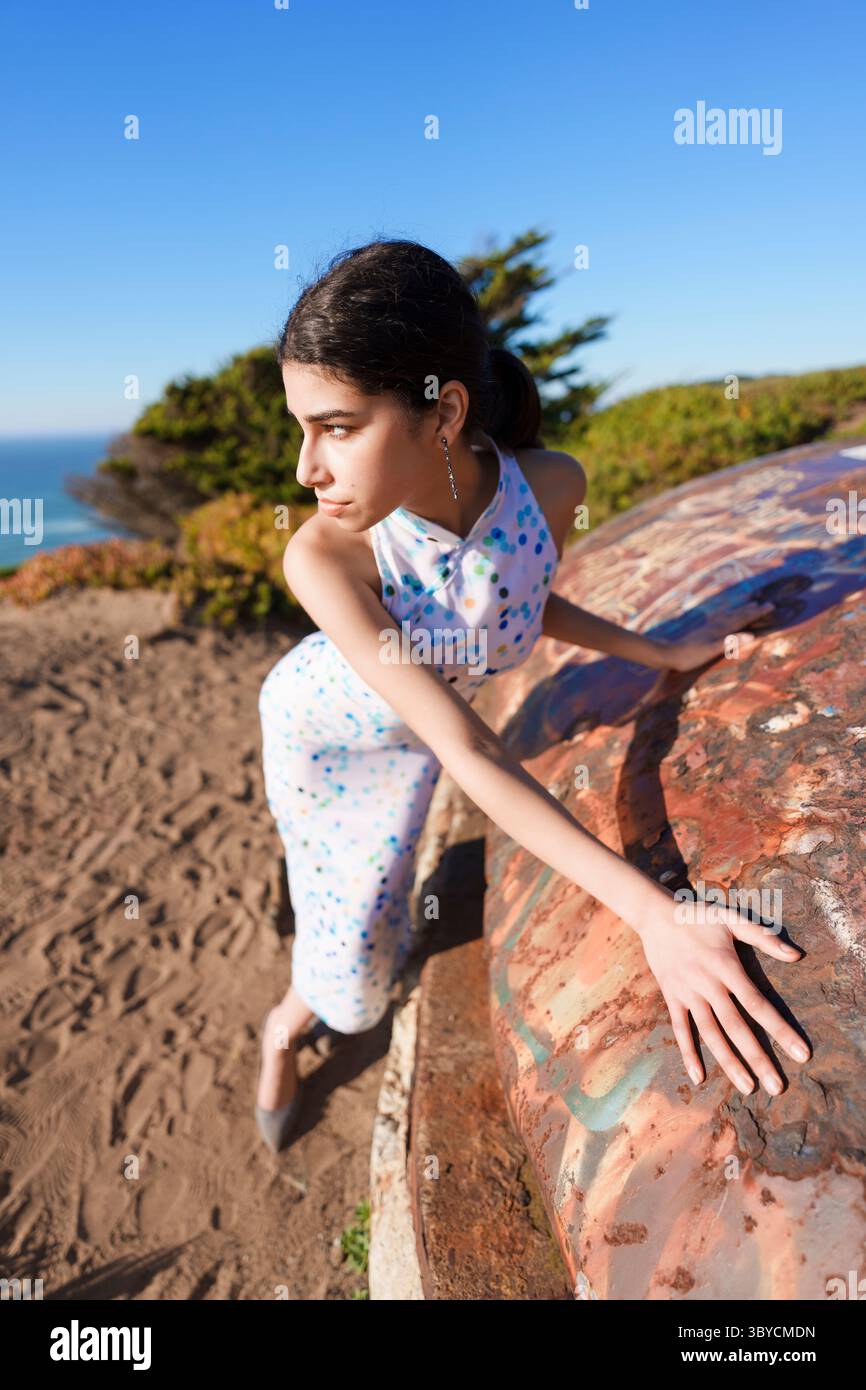Elegant Woman in Polka Dot Dress Posing Outdoors on Coastal Cliff Stock Photo