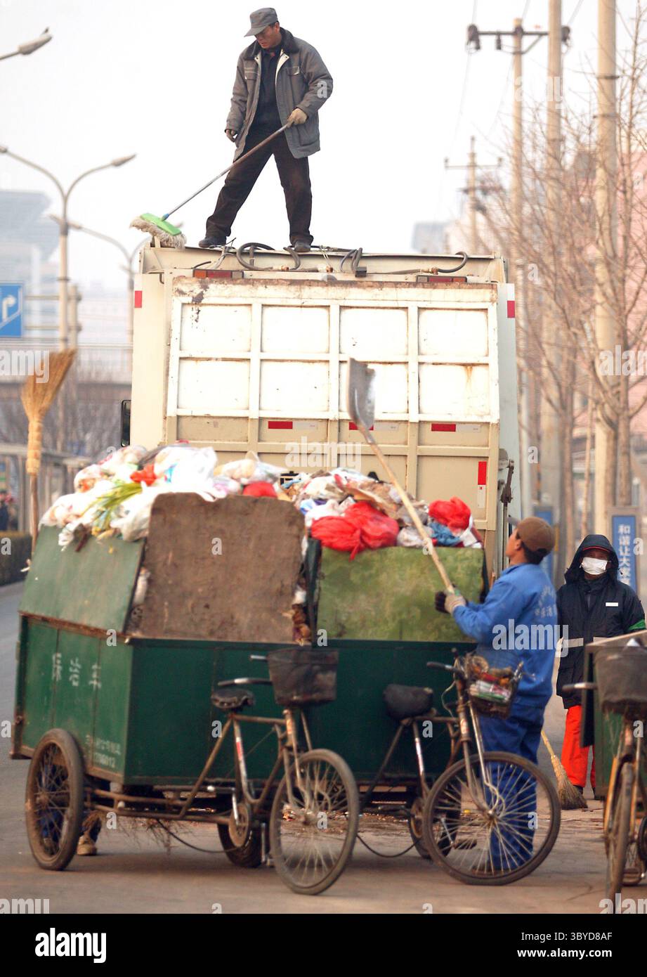 February 3, 2009, BEIJING, CHINA: A Chinese man cleans the top of his garbage truck while stopped to collect neighborhood trash in central Beijing February 03, 2009.  The global economic slowdown that has hit the stock markets has struck the trash markets too. Commodity prices for recycled metals and papers took sharp dives last fall as demand for them in China and elsewhere slackened. (Credit Image: © Stephen Shaver/ZUMA Press Wire) Stock Photo