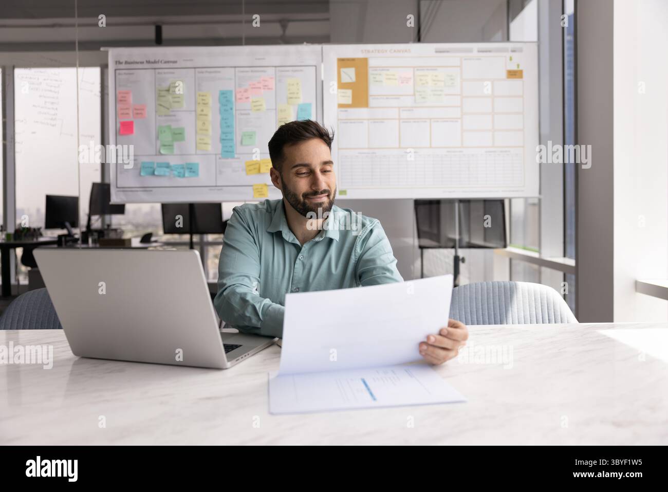 Smiling Hispanic man reviewing documents or financial report Stock Photo