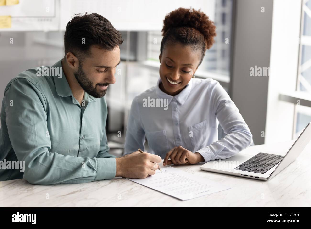 Man signing contract during meeting with young professional African ...