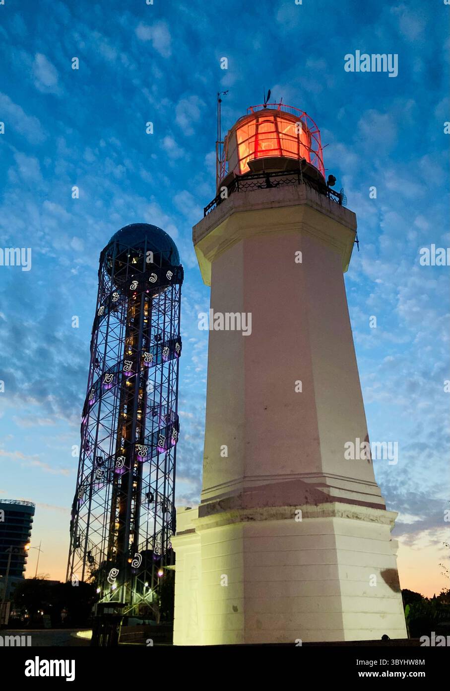 Modern lighthouse and observation tower illuminated against a vibrant blue sky in Batumi, Georgia. Located along the Black Sea coast. - Smartphone Captured Stock Image