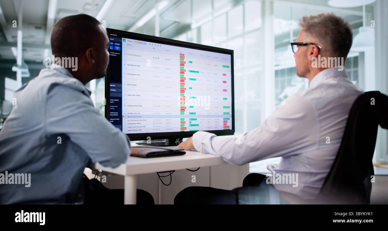 Focused Business Team Analyzing Reports On Multiple Computer Screens Together. Stock Photo