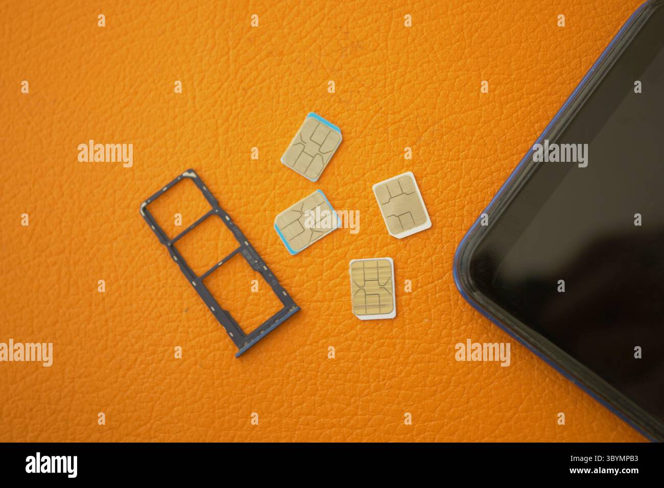 SIM card tray and multiple SIM cards on an orange surface Stock Photo