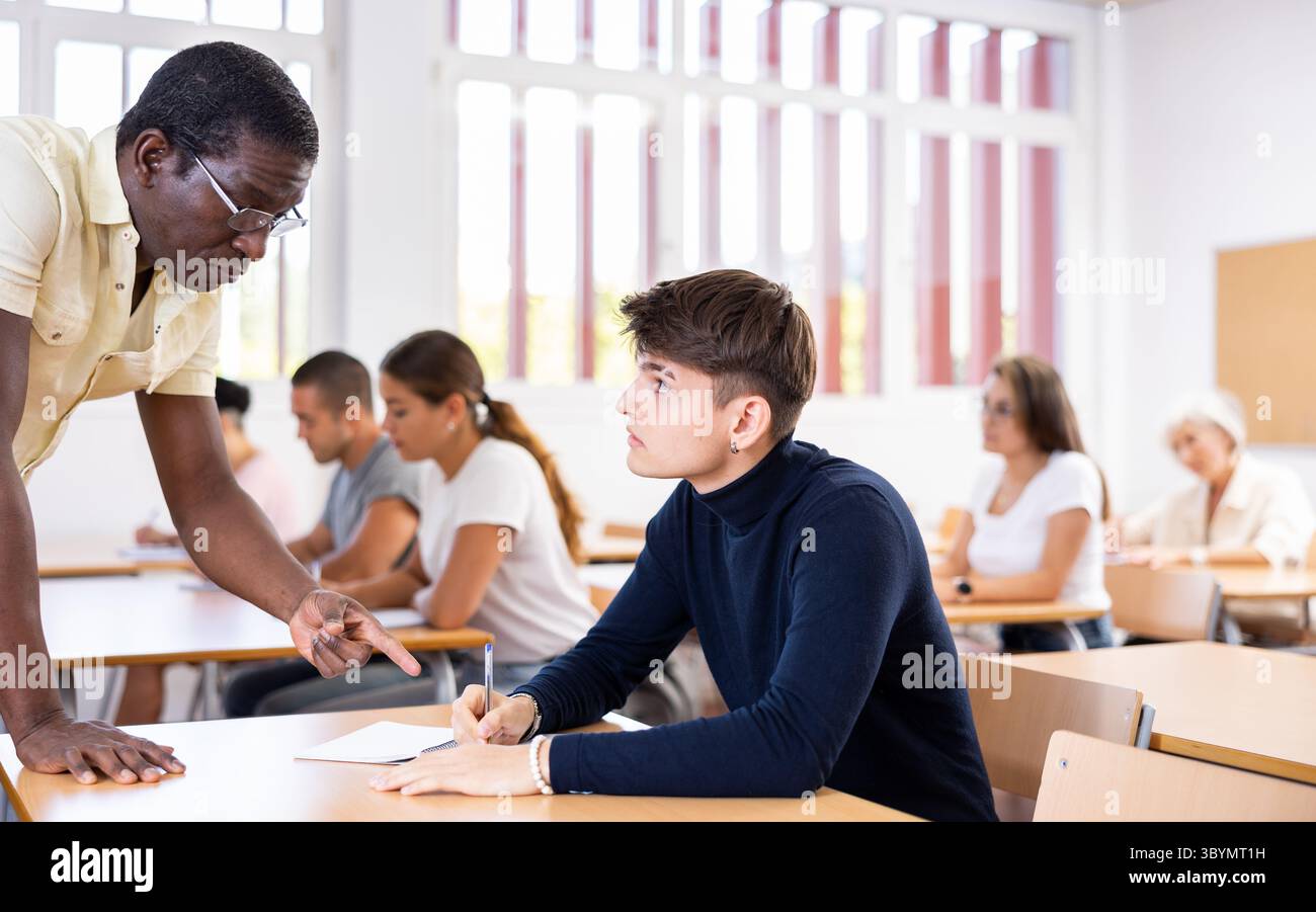 African American teacher helping student solve task during lesson Stock Photo