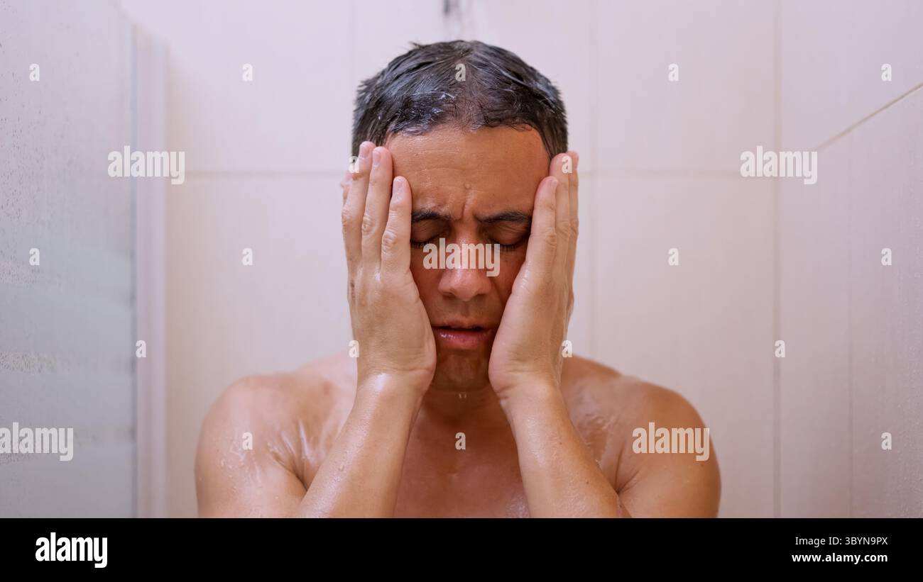 Sad man covering his face with hands while taking a shower Stock Photo