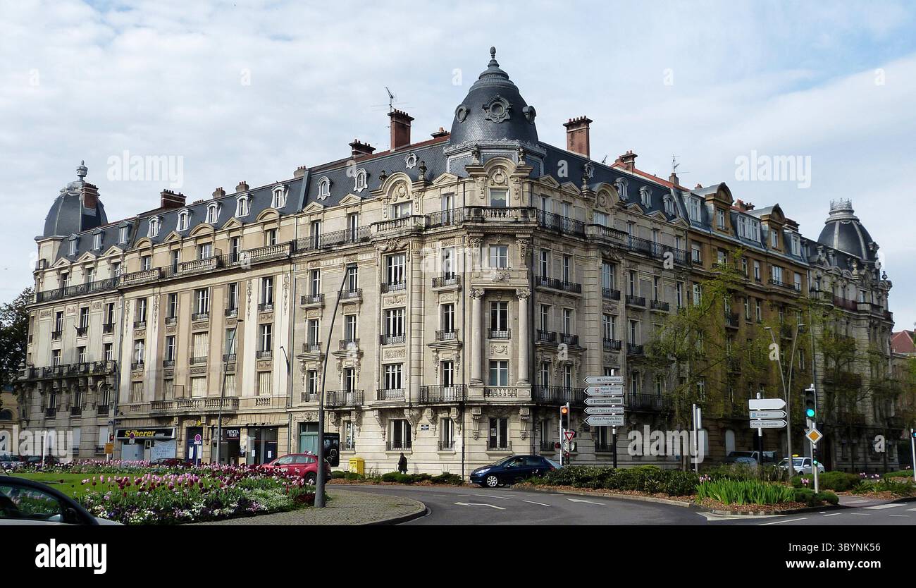 Metz, France – April 28, 2012. Historic building at Place Raymond Mondon in Quartier Imperial of Metz. View with cars, commercial properties and peopl Stock Photo