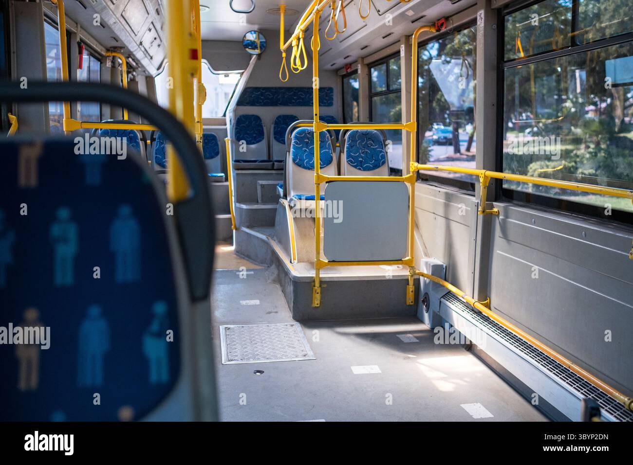 An empty public bus interior reveals blue patterned seats, yellow ...