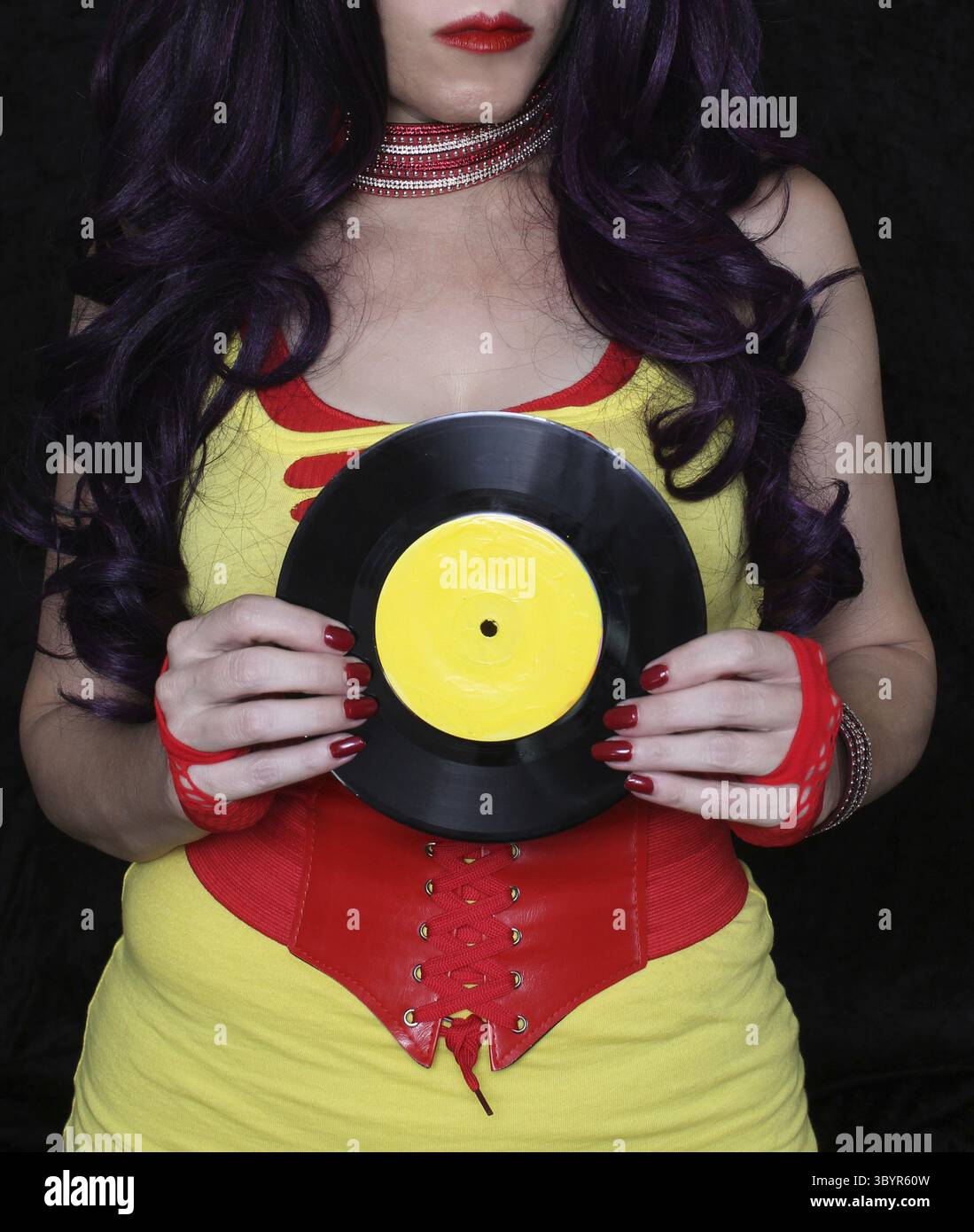Frau in den 1980er Jahren gelbe Kleidung mit 45 rpm Rekord. Plattenlabel mit gelber Plakatfarbe lackiert Stock Photo