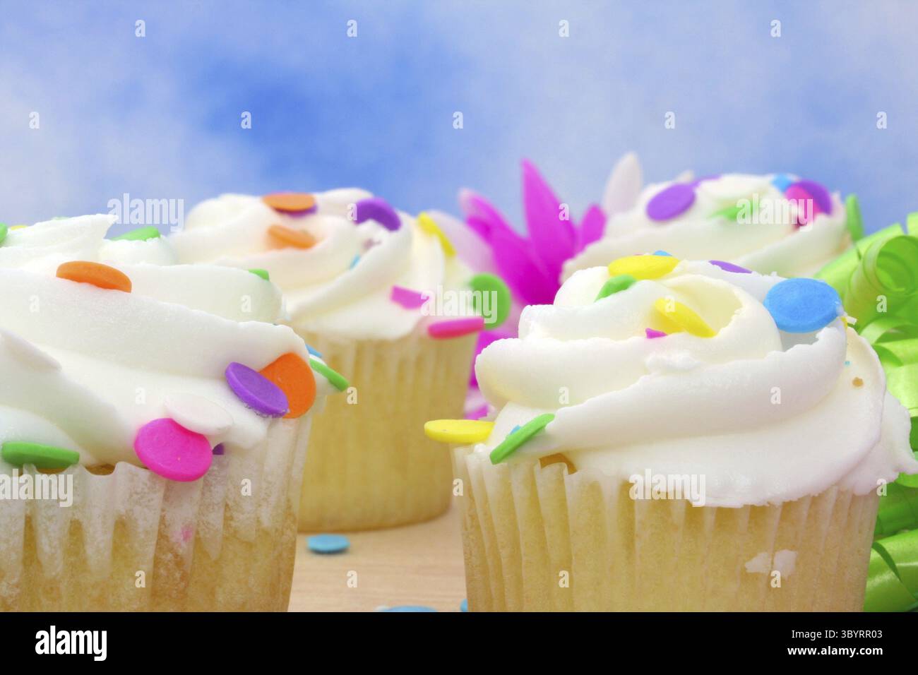 Cupcakes with brightly colored sprinkles on blue background Stock Photo