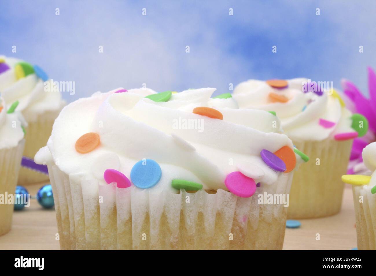 Cupcakes with brightly colored sprinkles on blue background Stock Photo
