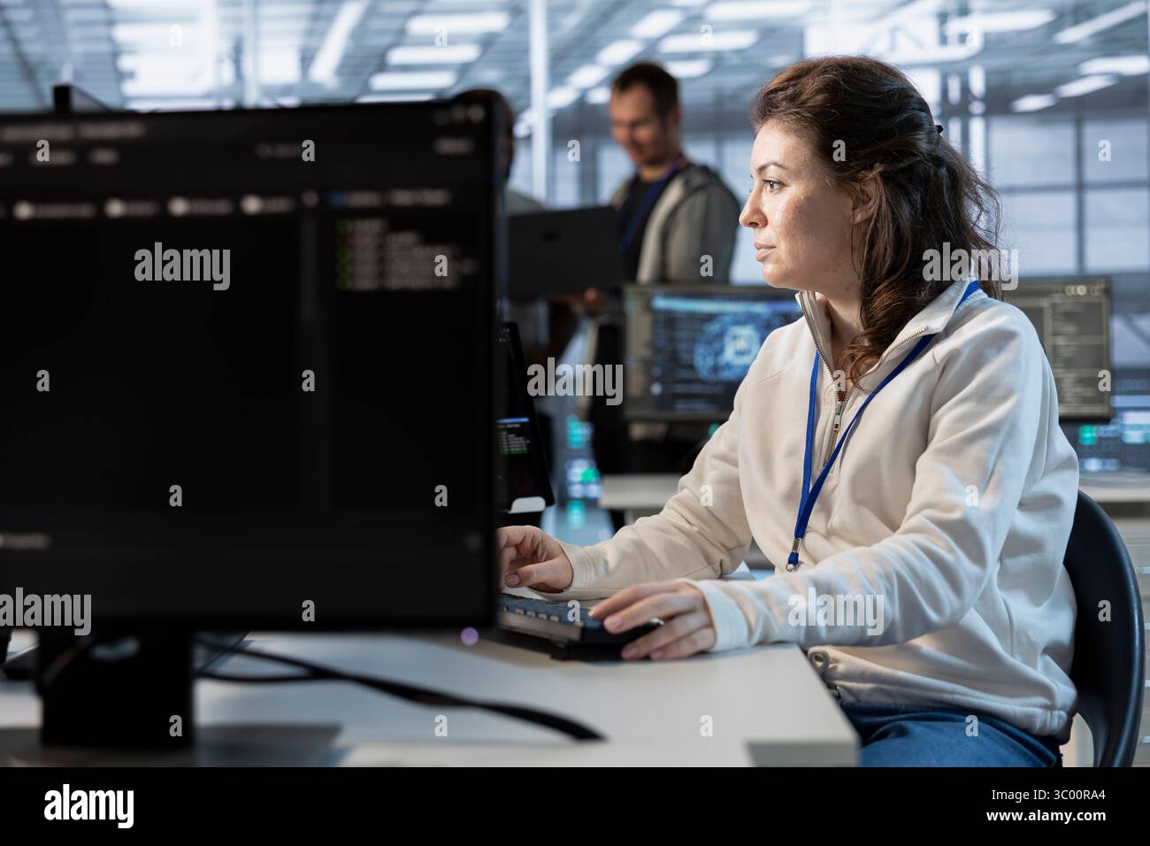System administrator in data center coordinating deployment of server architecture, improving data processing speed. Woman in server farm configuring and testing hardware using PC Stock Photo