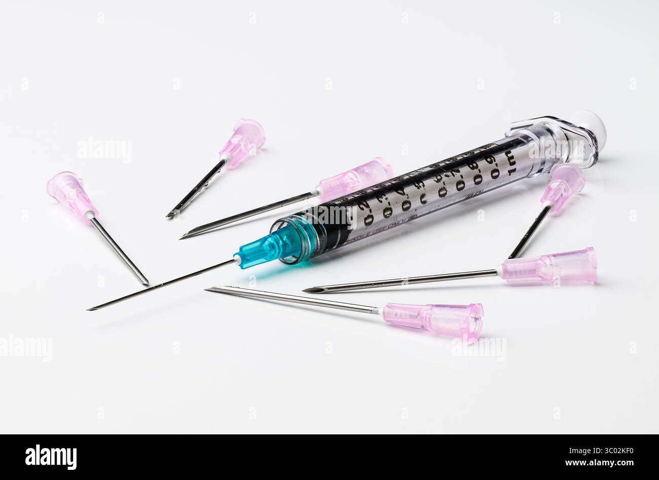 Medical syringe with blue needle and multiple pink needles on white background Stock Photo