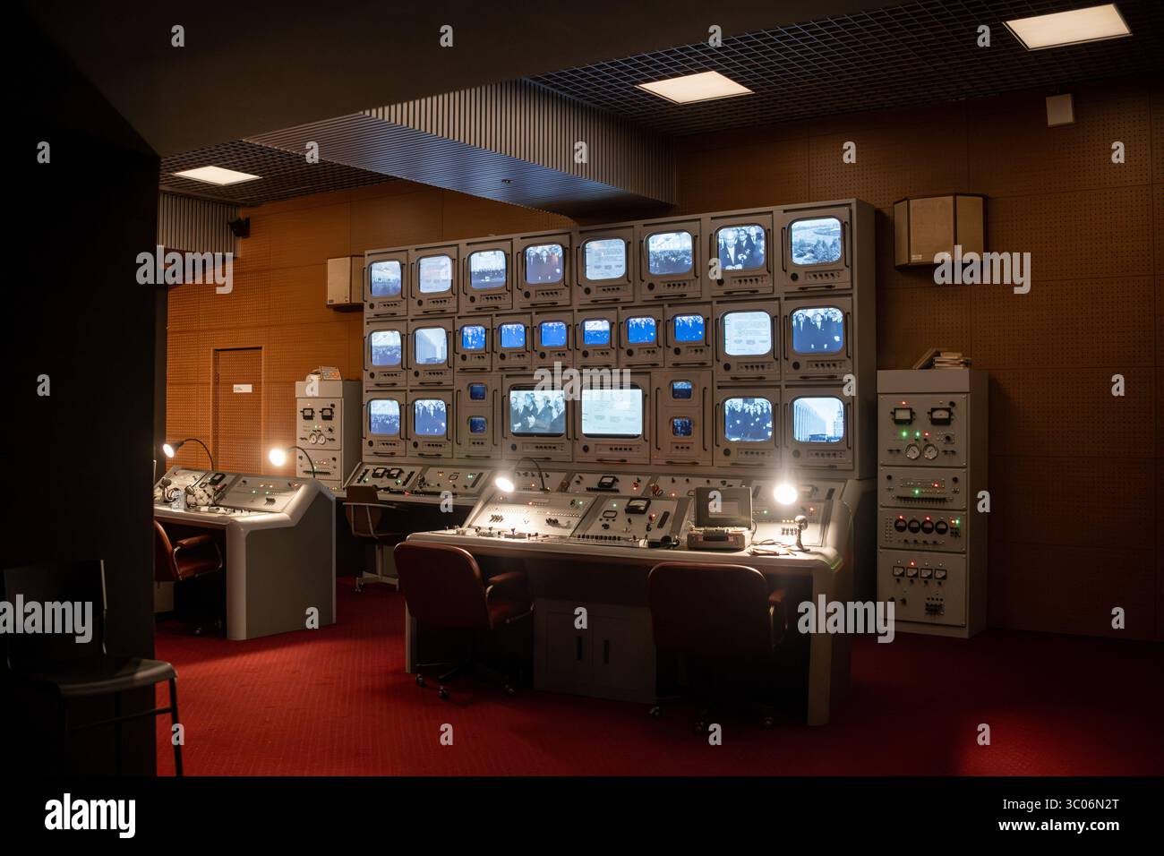 Vintage control room with monitors showing images, lit by overhead ...