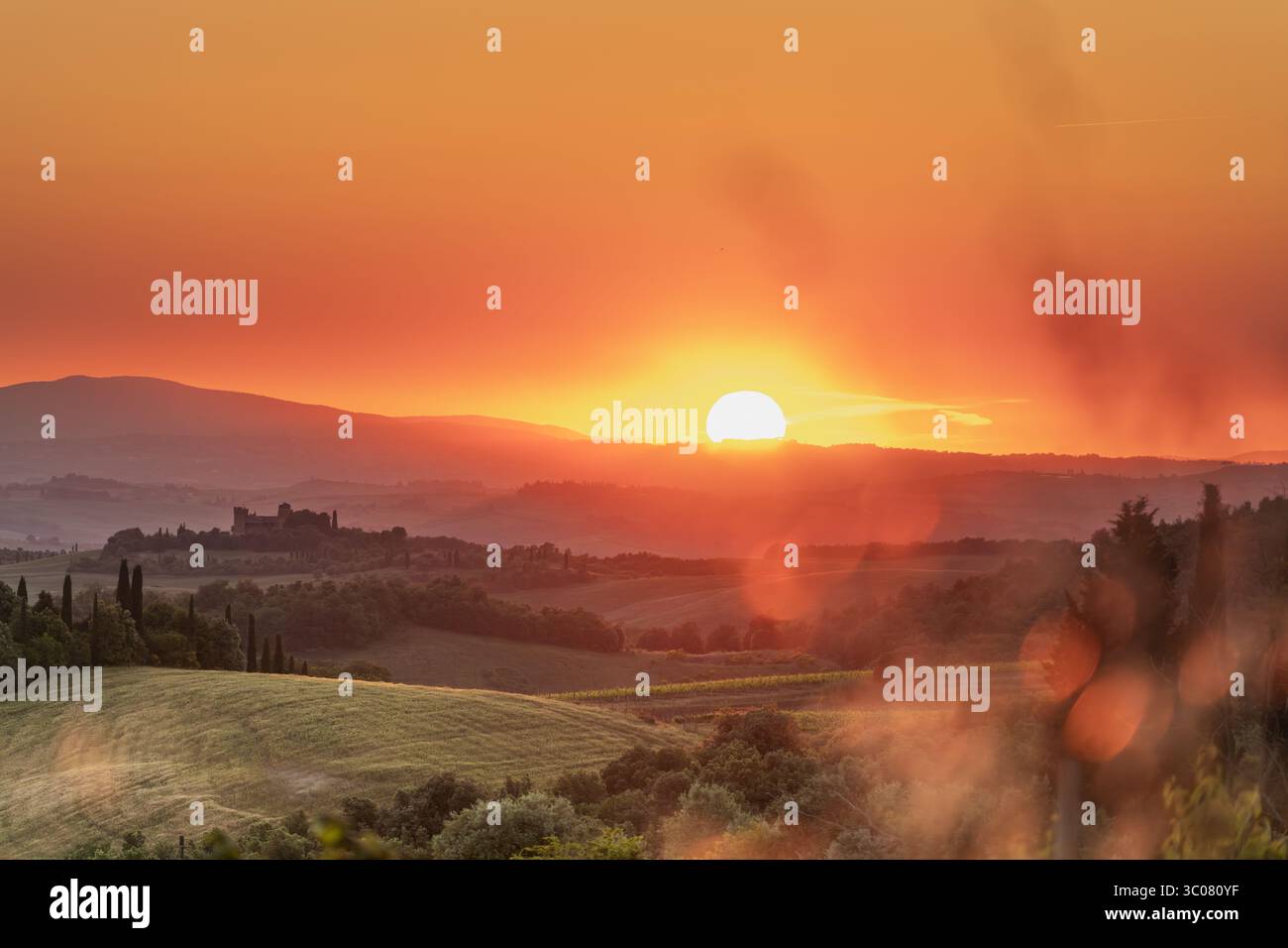 Tuscan sunset bathes rolling hills and a distant castle in golden light ...