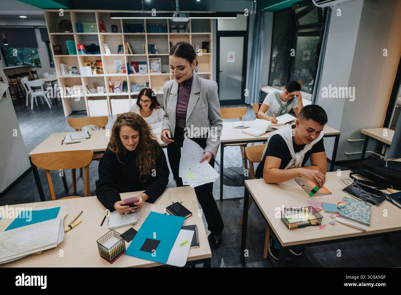Engaged teacher interacting with students in a modern classroom setting ...