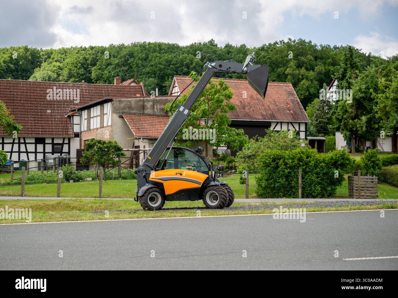 Telescopic loader with raised bucket parked near traditional ...