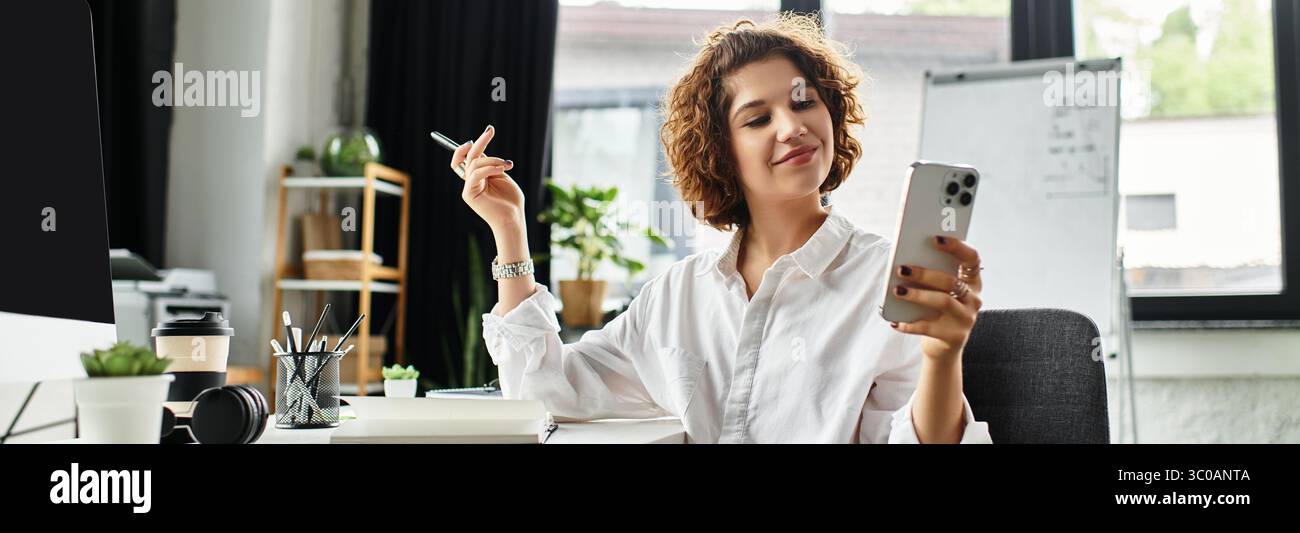 Curly-haired businesswoman enjoys her workday while using her smartphone at a stylish office, banner Stock Photo