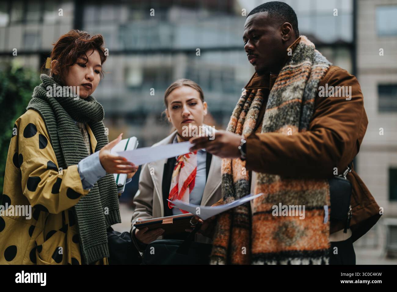 Multiracial Team Collaborating and Discussing Documents Outdoors in an Urban Setting Stock Photo