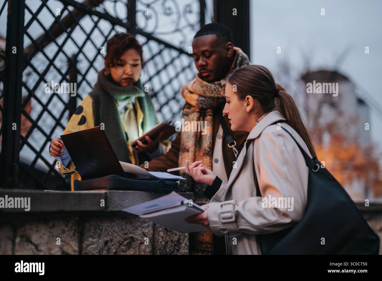 Multiracial people collaborating outdoors with a laptop and documents Stock Photo