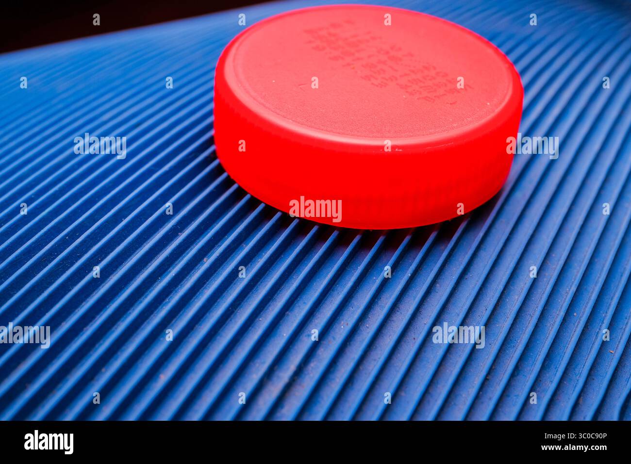 Red Plastic Bottle Cap on Blue Textured Surface Stock Photo