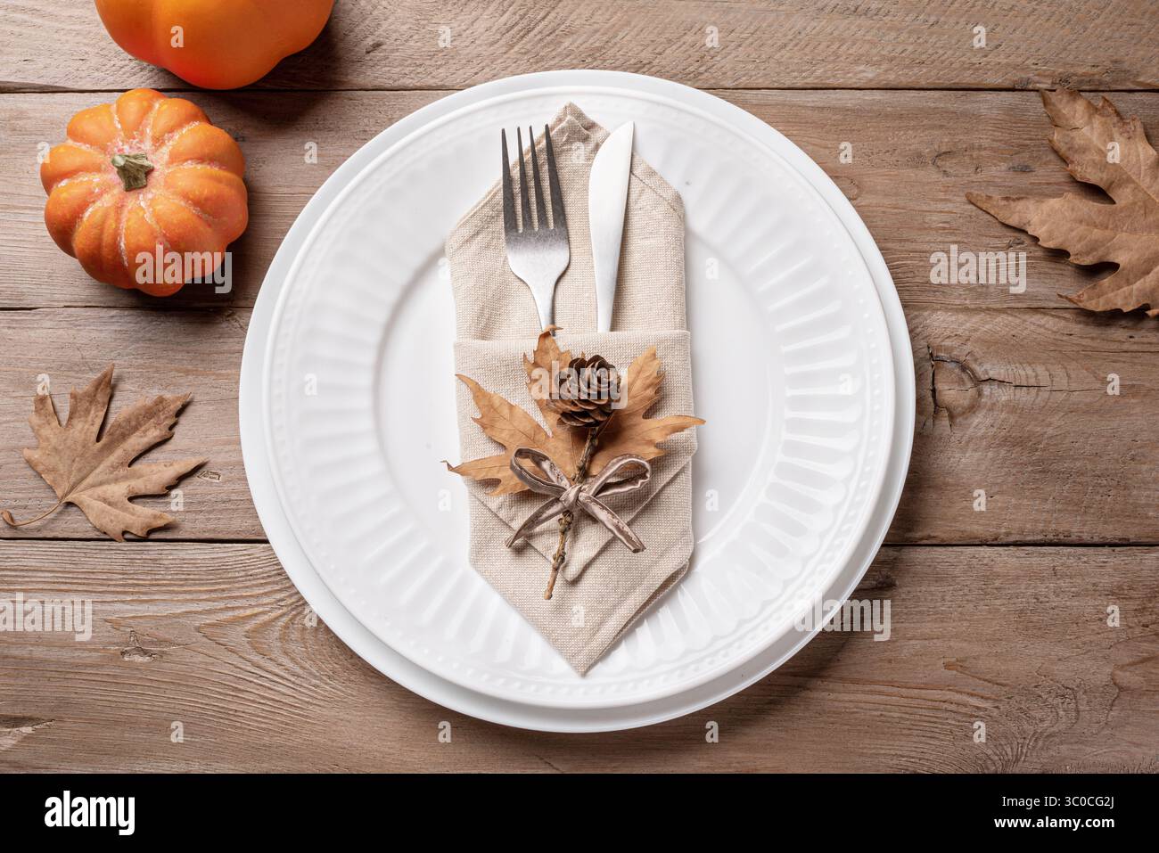 Thanksgiving Day or Halloween  place setting with pumpkins and dry maple leaves on wooden background, top view. Neutral autumn holiday table setting. Stock Photo