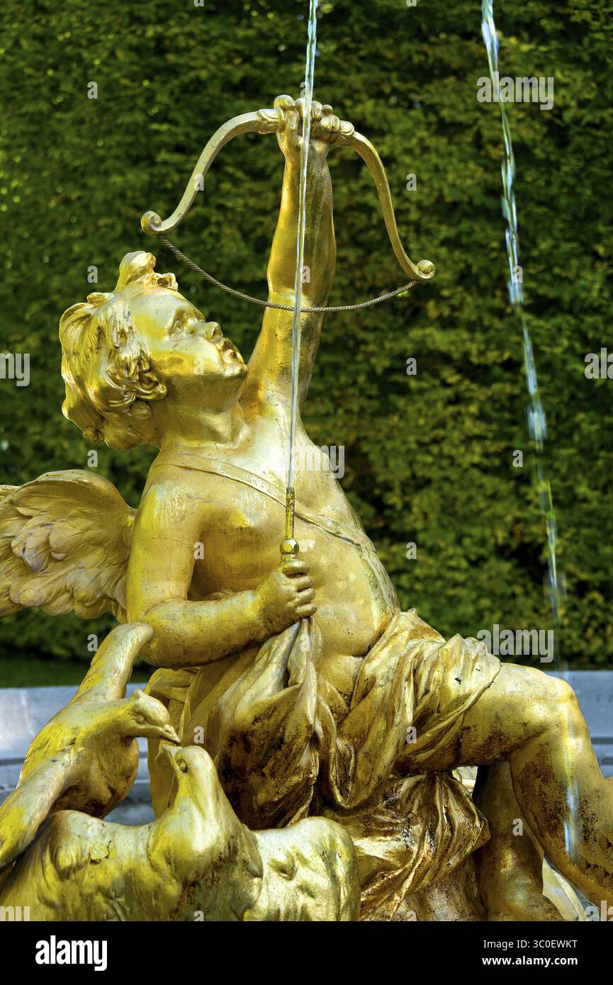 Fountain figure of Cupid, god of love, in gold with bow and arrow, Rococo style, east parterre, park of Linderhof Castle, UNESCO World Heritage Site, Stock Photo