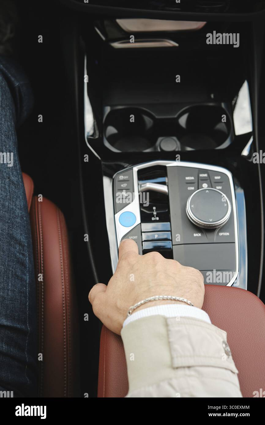 A driver is adjusting the controls in a luxury vehicle. The focus is on ...